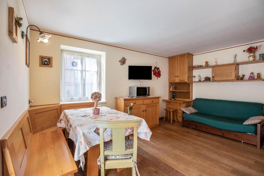 ein Wohnzimmer mit einem Tisch und einem grünen Sofa in der Unterkunft Appartamento Le Coccinelle in Varena