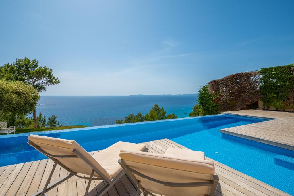a villa with a pool and two chairs on a deck at Herce Property - Minimalist & Mediterranean in Llucmajor