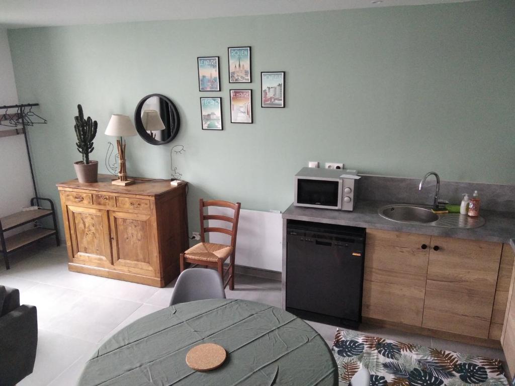 une cuisine avec un évier et un micro-ondes sur un comptoir dans l'établissement Agréable Maison proche Etretat, à Criquetot-lʼEsneval