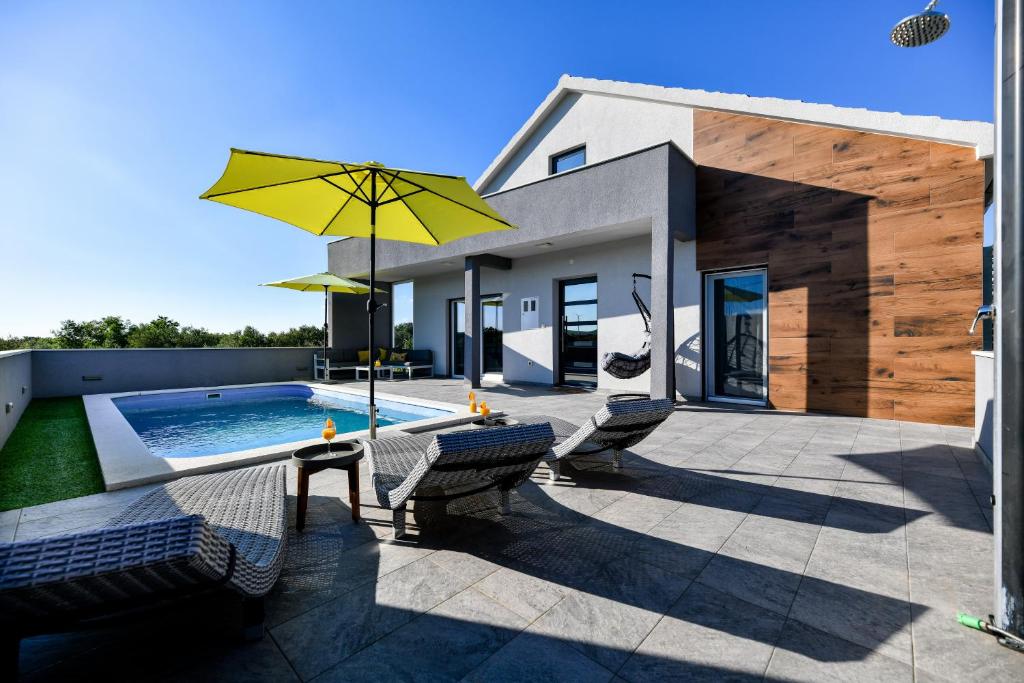 un patio con sillas y una piscina con sombrilla amarilla. en Luxurious Villa Natali, en Pridraga