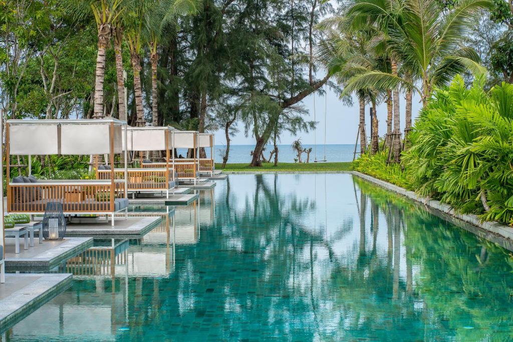 einen Pool in einem Resort mit Stühlen und Palmen in der Unterkunft Meliá Phuket Mai Khao in Mai Khao Beach