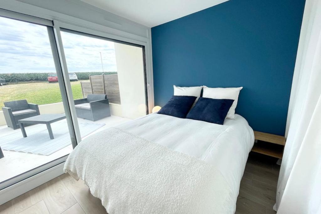 um quarto azul com uma cama e uma grande janela em T3 Neuf Archi Cocooning - Terrasse - Face à la mer em Ploemeur