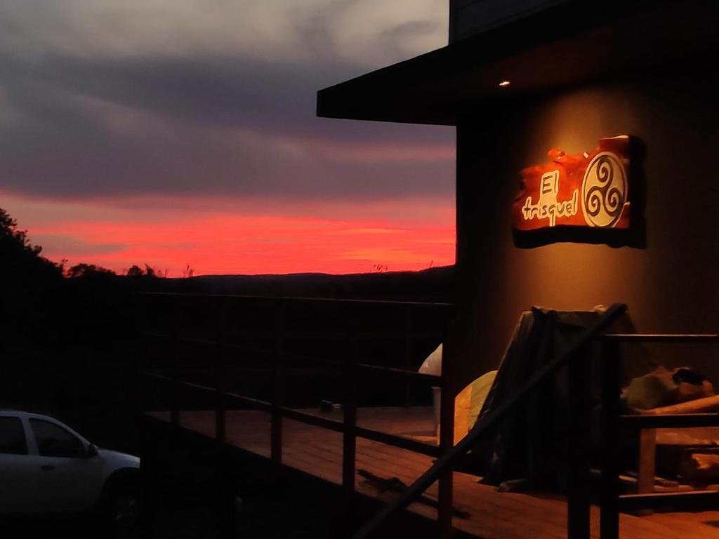 ein Gebäude mit einem Schild mit Sonnenuntergang im Hintergrund in der Unterkunft Cabaña El Trisquel in Villa Serrana