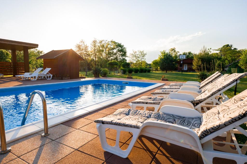 a row of lounge chairs next to a swimming pool at Tenisz Vendégház in Ordacsehi