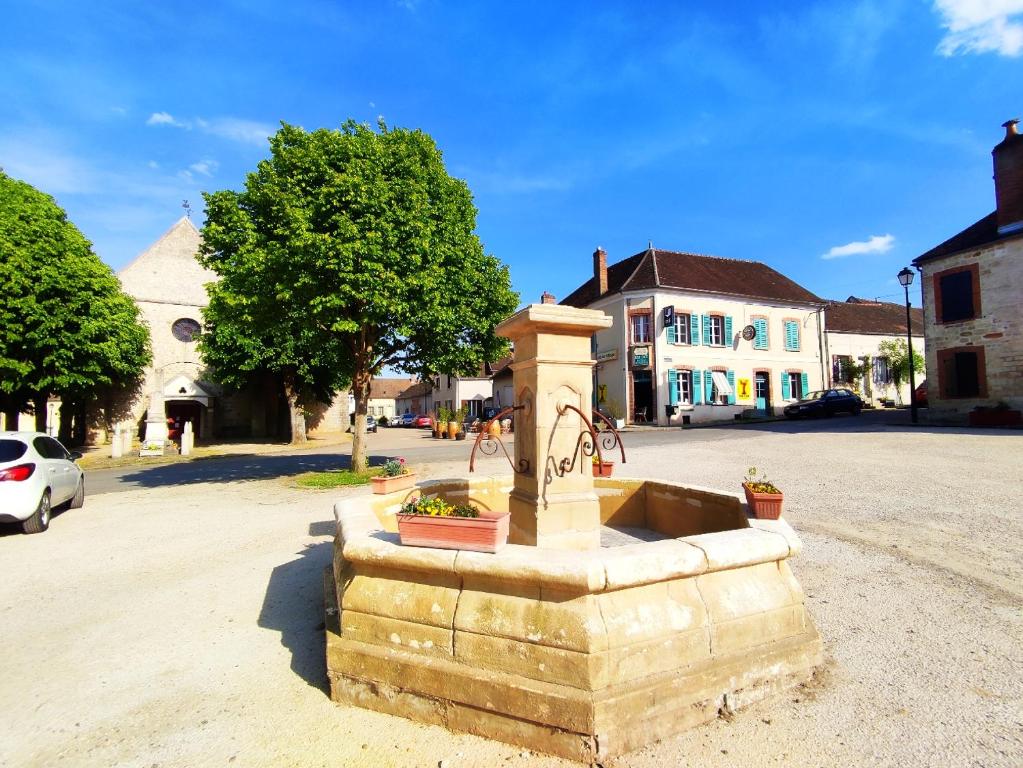 a stone fountain in the middle of a street at Maison de village - Suite Baroque cosy et élégante à 1 h de Paris proche Fontainebleau 