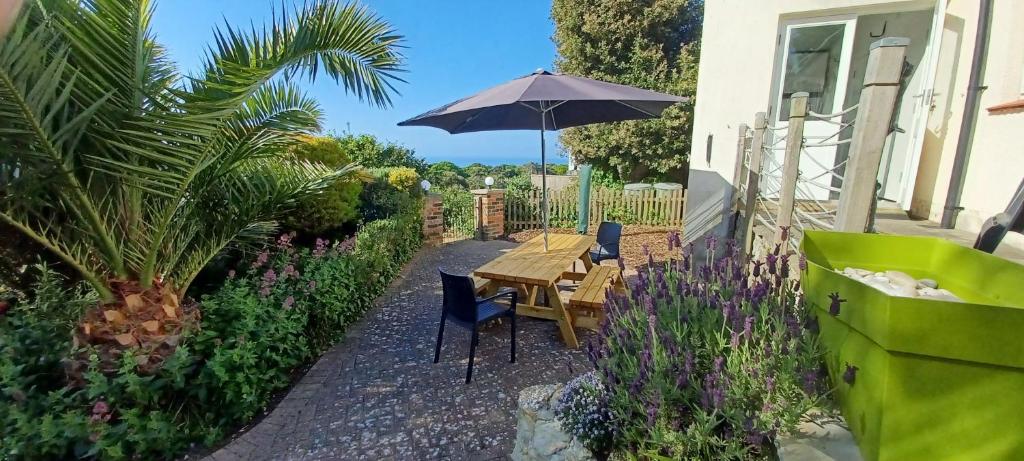 a table and chairs with an umbrella in a garden at Sea Grove in Ventnor