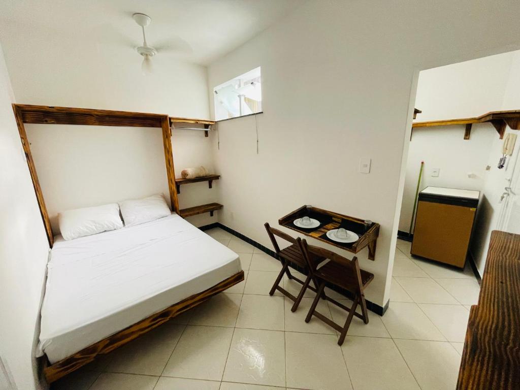a small bedroom with a bed and a table at Kitnet encantadora, equipada, conforto no centro in Caratinga