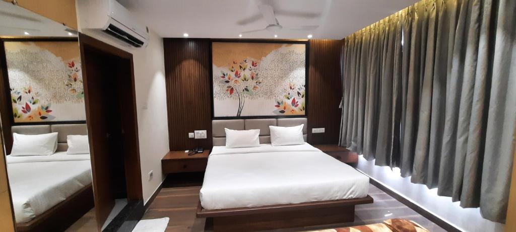 a hotel room with two beds and paintings on the wall at HOTEL SUNRISE HOSPITALITY in Vijayawāda