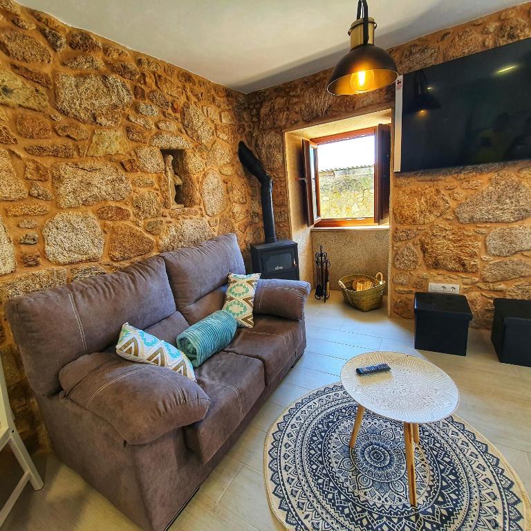 a living room with a couch and a stone wall at Casa Jalecha in Muxia