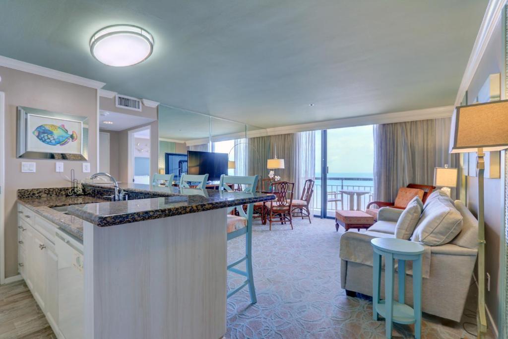 a hotel room with a kitchen and a living room at Gorgeous San Luis Condo Amazing Pool Amenities Ocean Views From 2 Balconies in Galveston