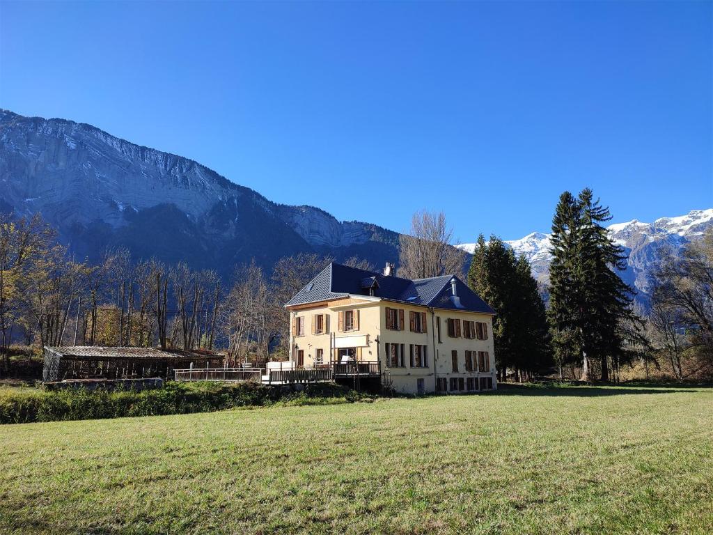 een groot huis in een veld met bergen op de achtergrond bij BO LODGE in Le Bourg-dʼOisans