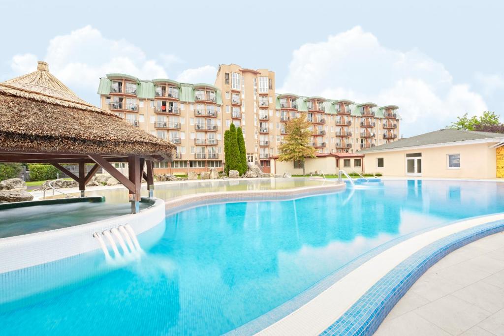 a swimming pool with a hotel in the background at Hotel Europa Fit Hévíz in Hévíz