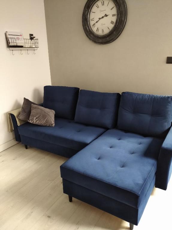 Sofá azul en la sala de estar con reloj en la pared en Siódemka, en Toruń