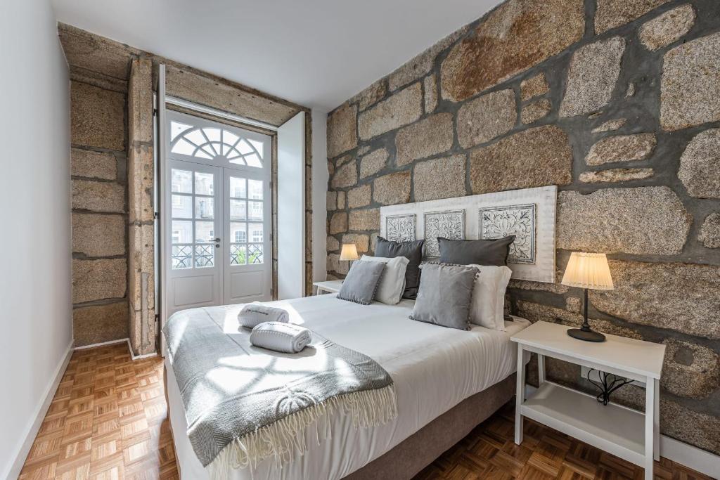um quarto com uma cama grande e uma parede de pedra em GuestReady - Grandeur River Terrace no Porto