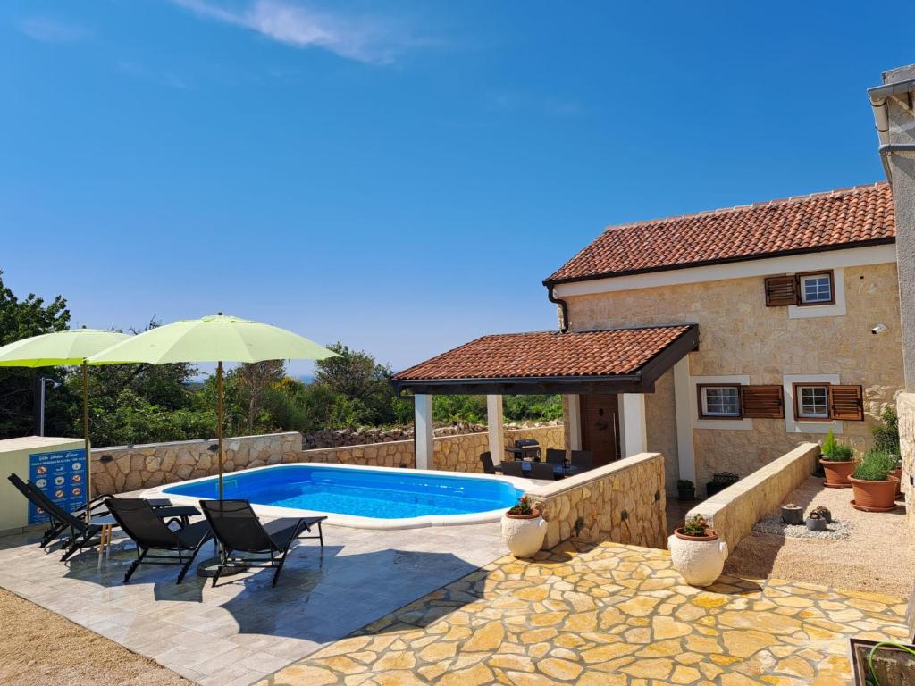 a pool with chairs and an umbrella next to a house at Villa Venkin Dvor in Novalja