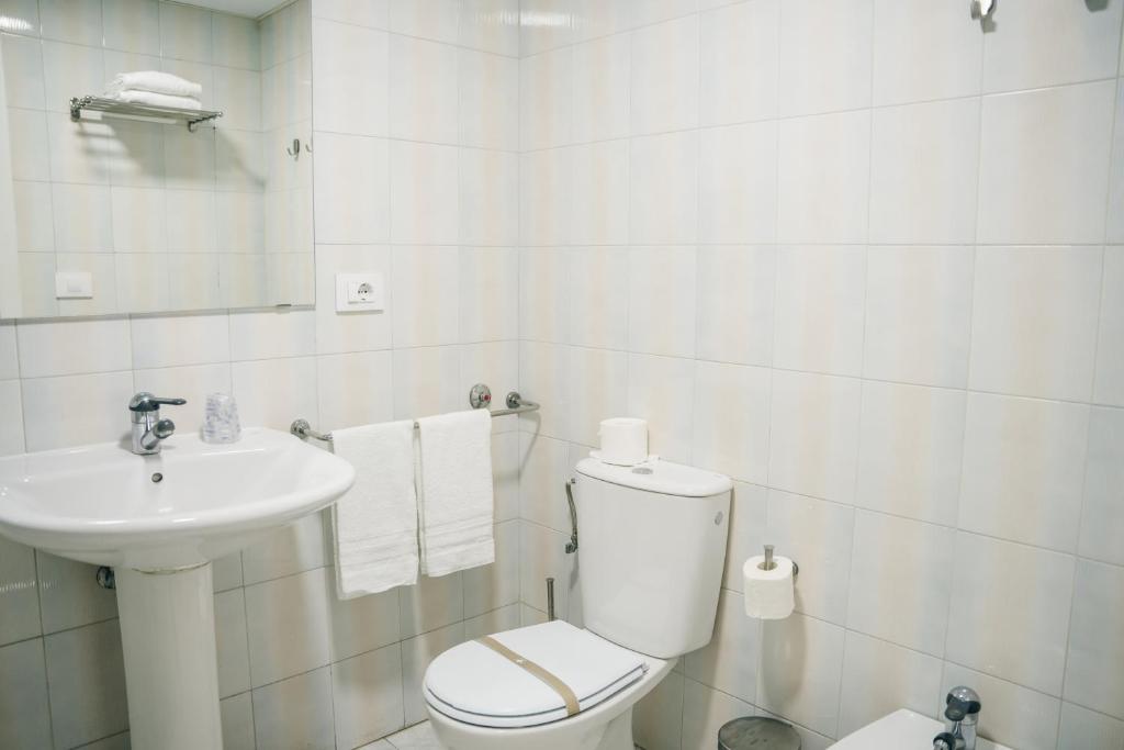 Un baño blanco con inodoro y lavabo. en Hotel Alda Estación Pontevedra, en Pontevedra