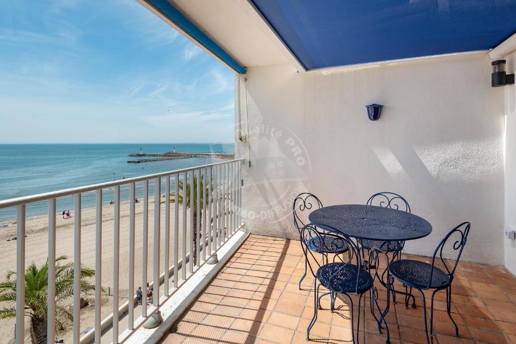 een balkon met een tafel en stoelen en het strand bij AS21932 - Appartement P3 magnifique Vue Mer en dernier étage sur le Front de Mer in Le Grau-du-Roi