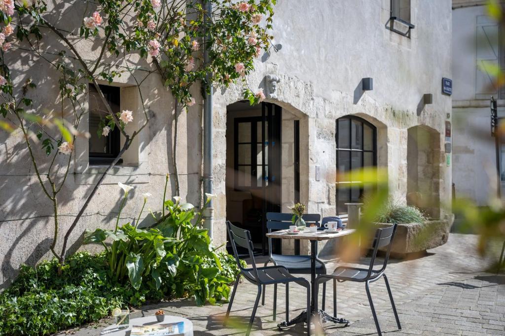 une terrasse avec une table et des chaises devant un bâtiment dans l'établissement Hôtel Saint Nicolas, à La Rochelle