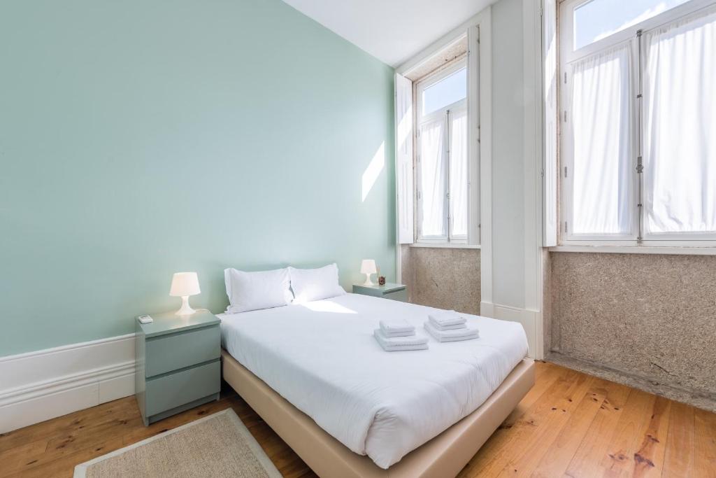 een slaapkamer met een wit bed en 2 ramen bij GuestReady - Porto Home 6 in Porto