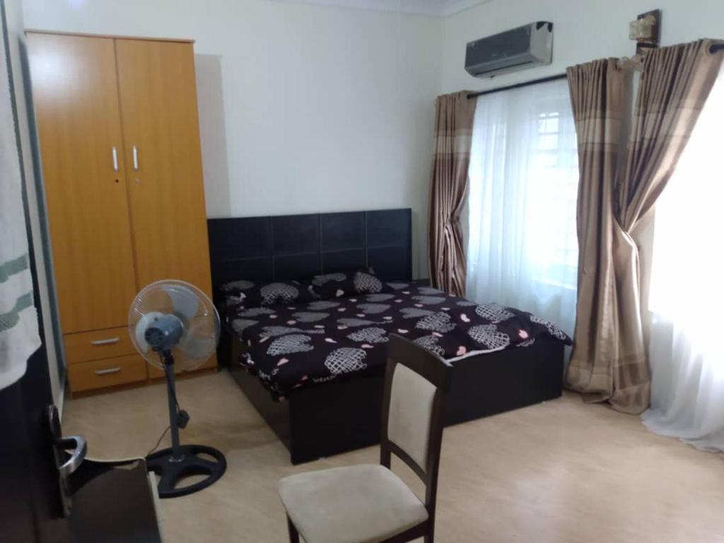2 bedroom service apartment with full services في Idimu: غرفة نوم بسرير وكرسي ومروحة