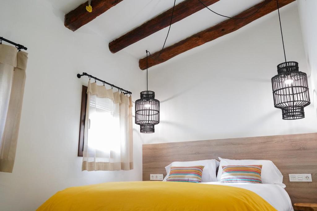 a bedroom with a yellow bed and two chandeliers at Apartaments la Rambla - Arbequina - 6 persones in Cornudella