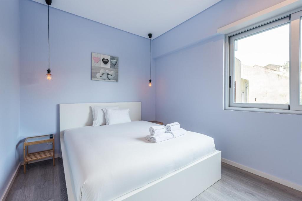 ein weißes Schlafzimmer mit einem großen weißen Bett und einem Fenster in der Unterkunft GuestReady - Wellspring Bloom in Porto