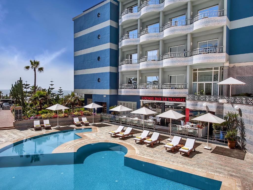 a hotel with a pool and chairs and umbrellas at Hôtel Club Val d'Anfa Casablanca Ocean view in Casablanca