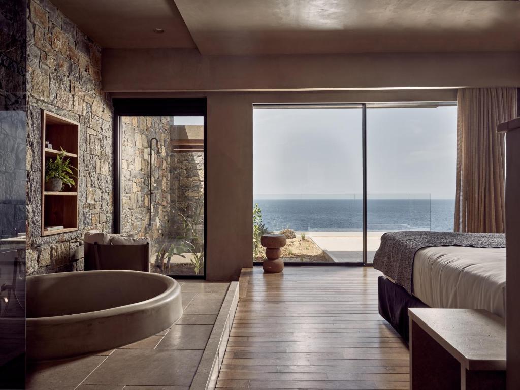 a bedroom with a tub and a bed with a view at Acro Suites - A Wellbeing Resort in Agia Pelagia