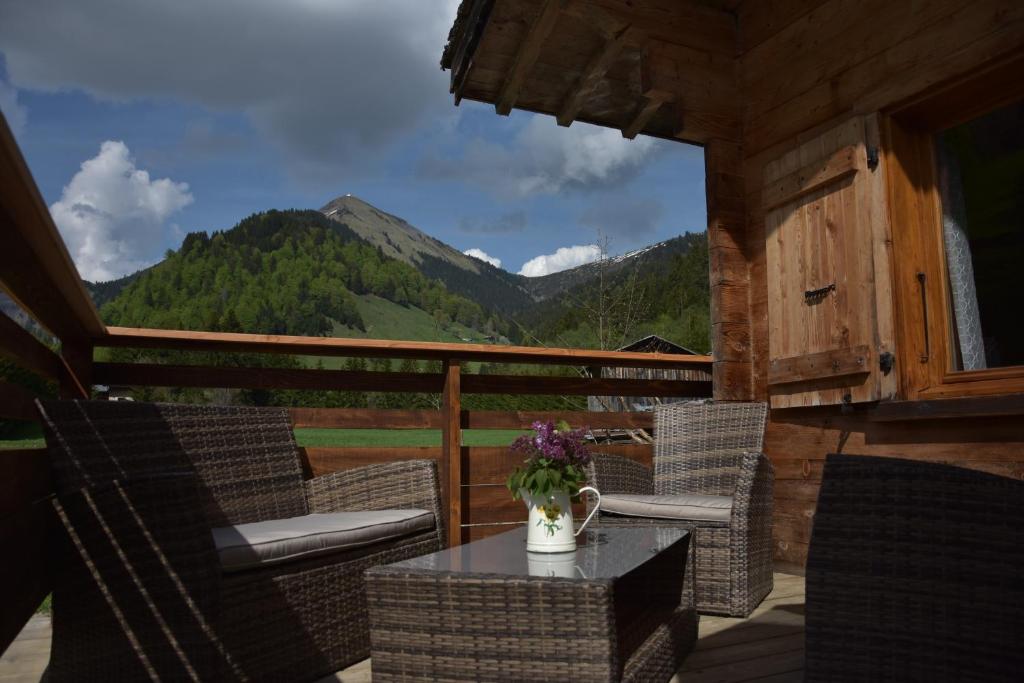 a porch with chairs and a table with a vase of flowers at Chalet L'Armoy in La Giettaz