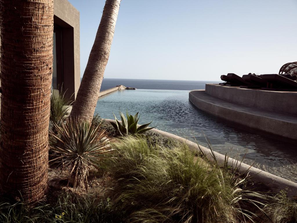 a view of the ocean from a resort with palm trees at Acro Suites - A Wellbeing Resort in Agia Pelagia