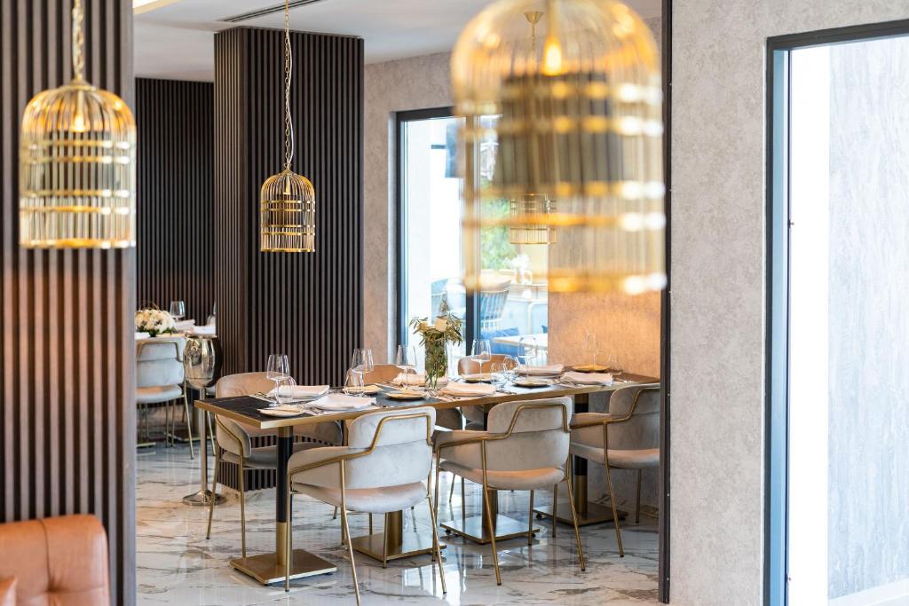 a dining room with a table and chairs and chandeliers at Hotel Millennium by Aycon in Budva