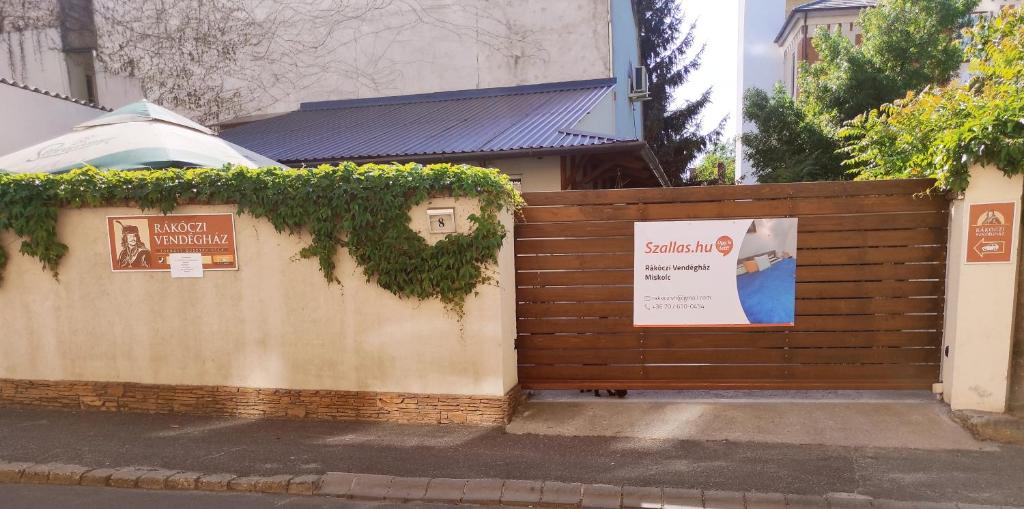 a wooden fence with a sign on it at Rákóczi Guesthouse Miskolc in Miskolc