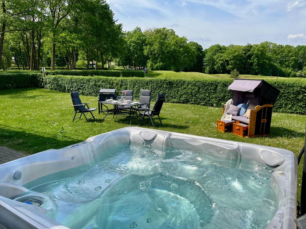 una bañera de hidromasaje en un patio con mesa y sillas en Blick ins Grüne- Premium-FeWo, en Göhren-Lebbin