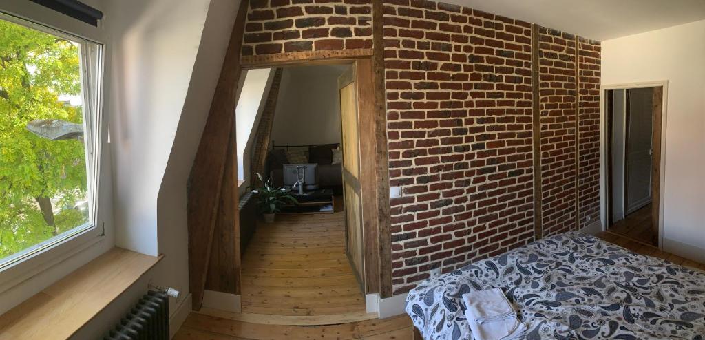 a hallway with a brick wall and a bed in a room at VIEUX LILLE Porte de Gand Bienvenue chez NESTYOU, Lille in Lille