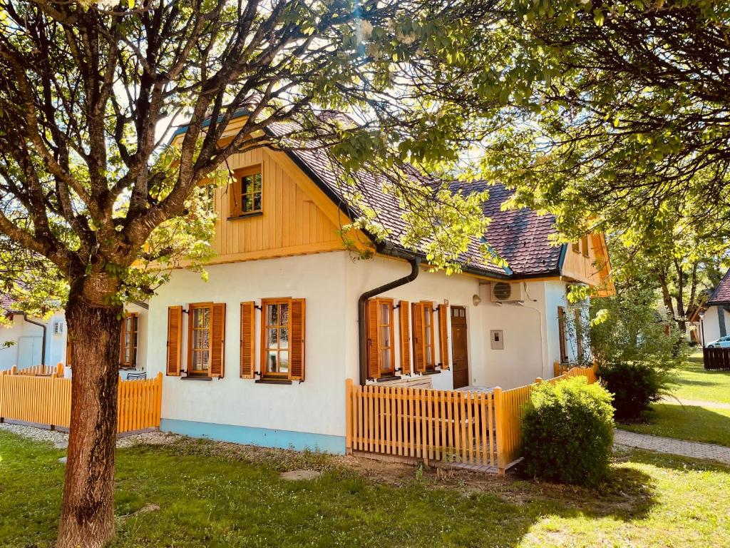 een huis met een oranje hek en een boom bij Moravska iža in Moravske-Toplice