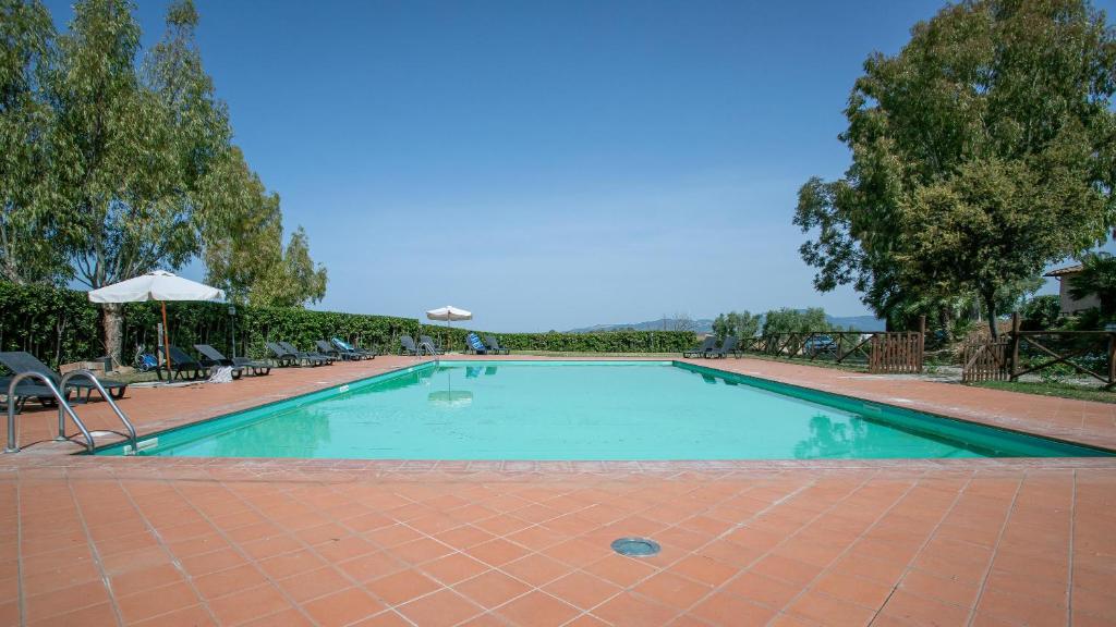 a large swimming pool with chairs and an umbrella at Appartamento Pianosa in Riotorto