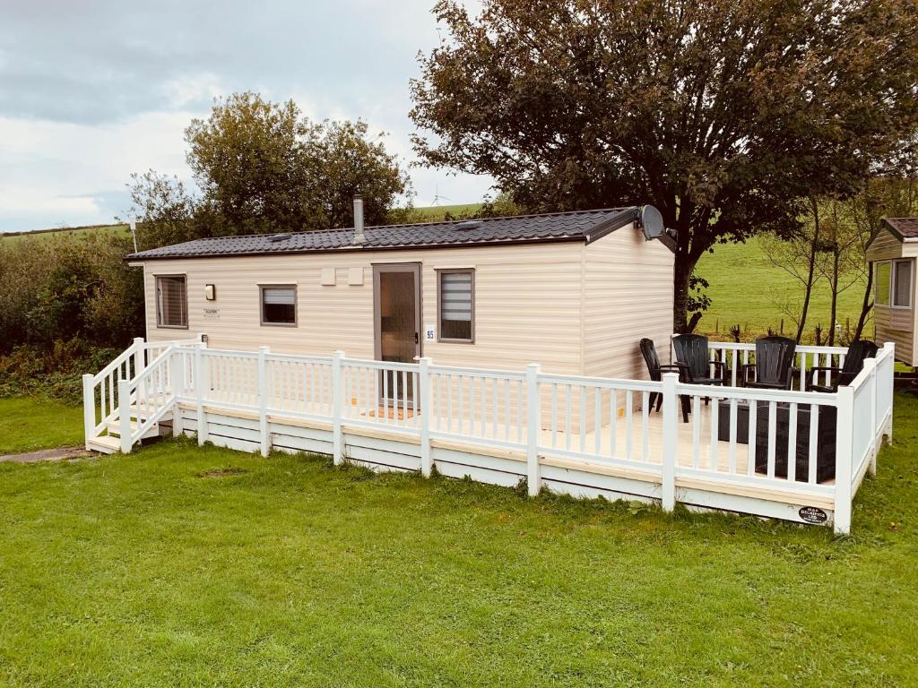 a white mobile home with a white fence at 95 Newquay bay Resort Dog friendly in Newquay