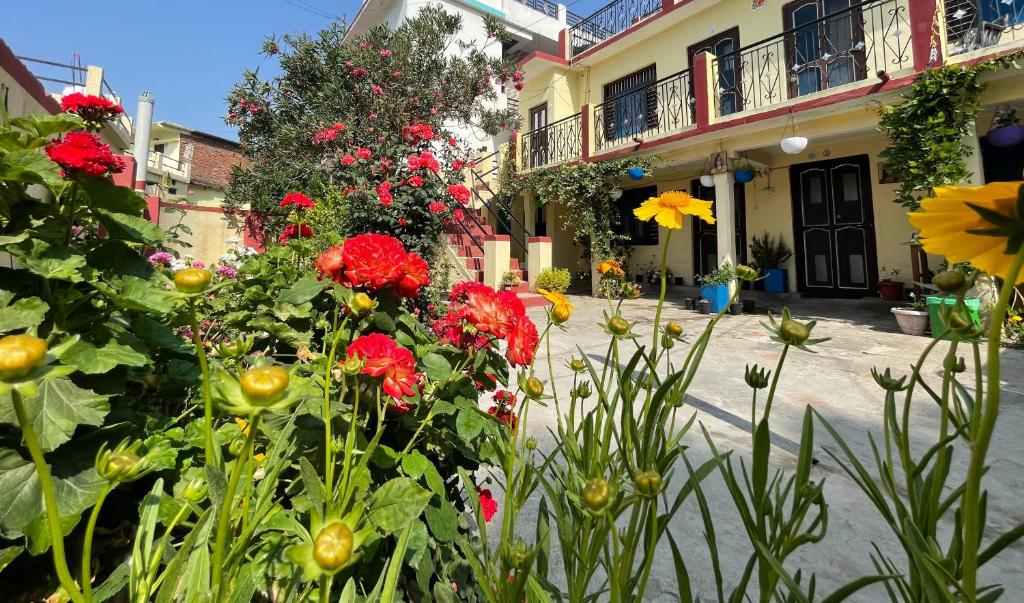 a garden with red flowers in front of a building at Katyuri Kings Divine Homestay- Babaji's cave in Dwārāhāt