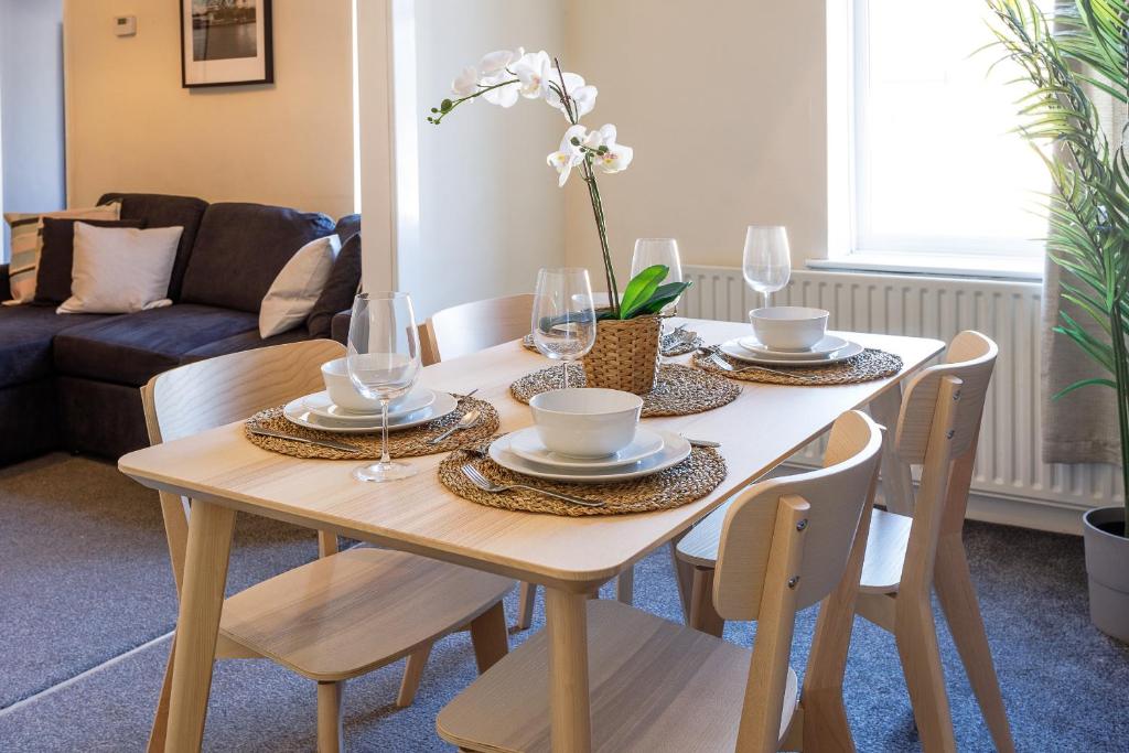 a dining room table with plates and glasses on it at Cozy Coastal Getaway in North Shields