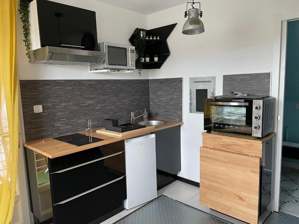 a small kitchen with a sink and a microwave at La maison du bonheur avec clim reversible in Larçay
