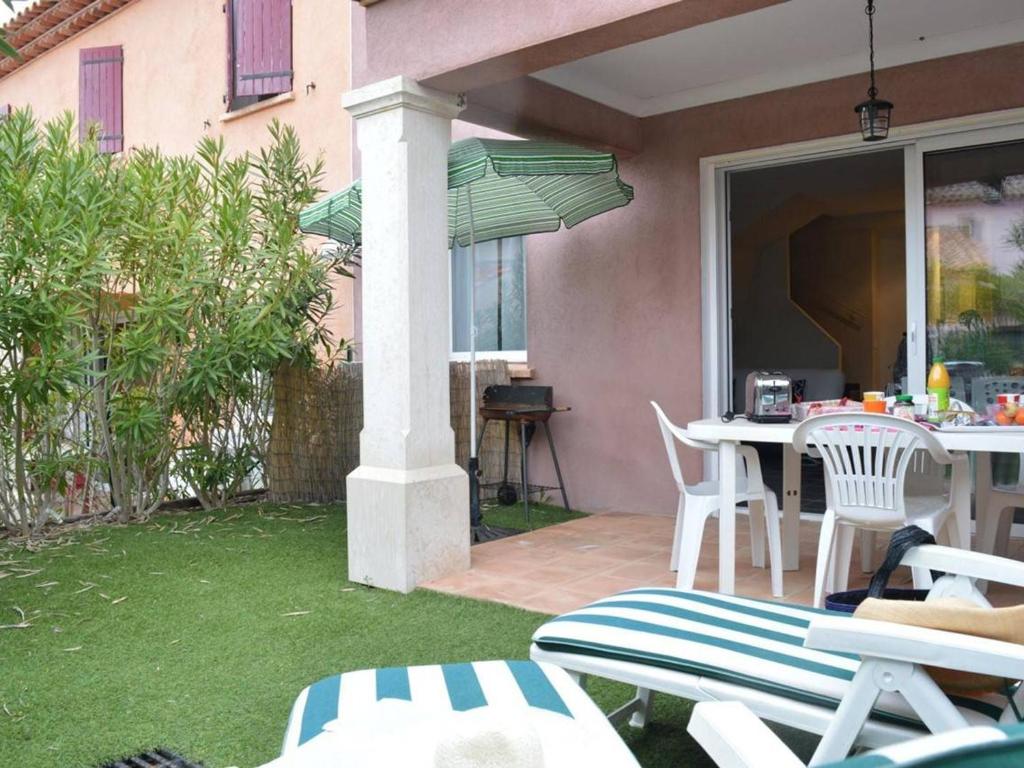 un patio avec une table, des chaises et un parasol dans l'établissement Maison moderne 4 pièces climatisée, proche plage, avec jardin, terrasse couverte et parkings sécurisés - FR-1-226-279, à Sainte-Maxime