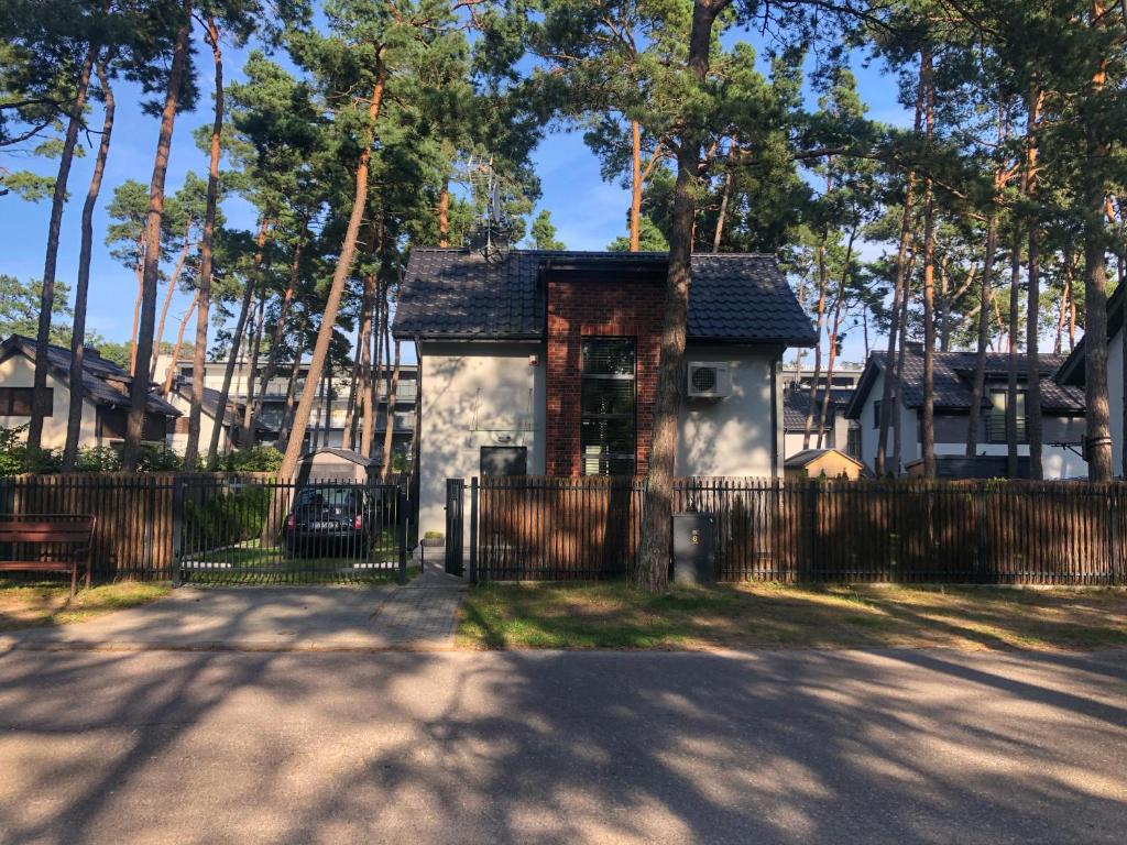 una pequeña casa blanca con una valla negra en Villa Ohana in Pobierowo 300 m from the beach en Pobierowo