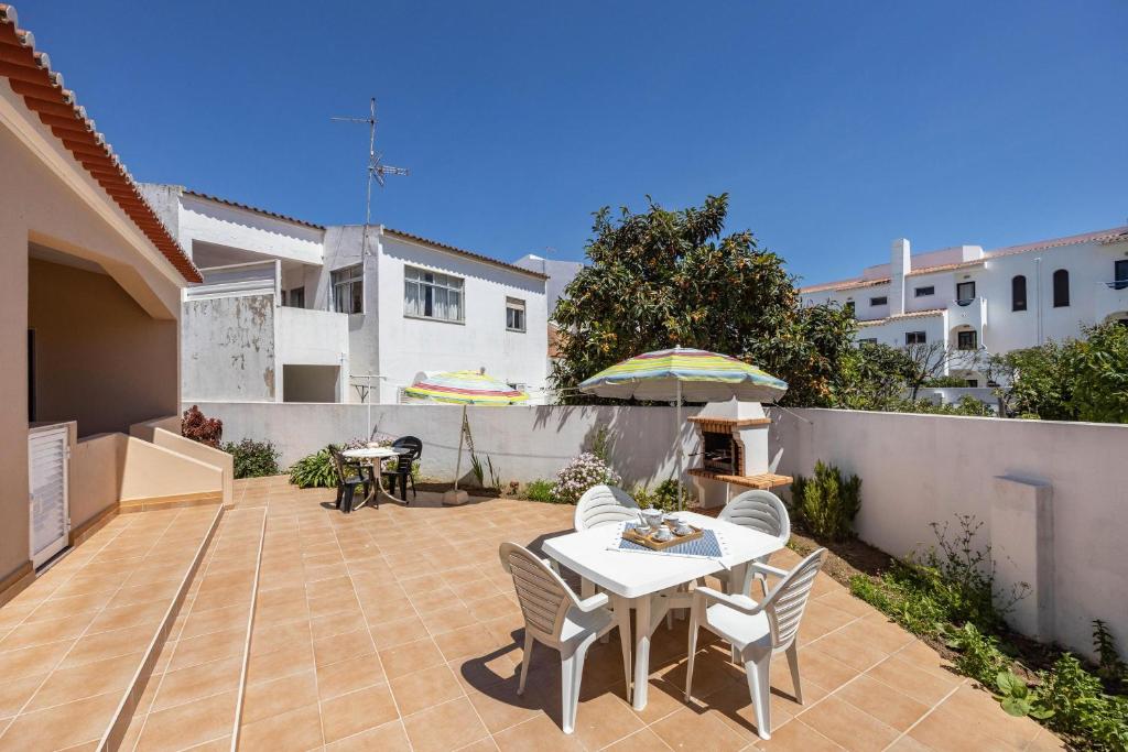 een terras met een tafel, stoelen en een parasol bij Casa Bege T1 in Burgau