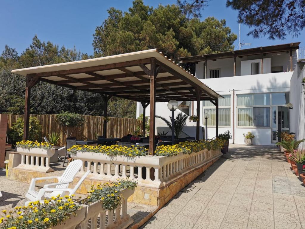 a pavilion with white benches and flowers in a yard at Bed And Breakfast Li Scianuli in Porto Cesareo