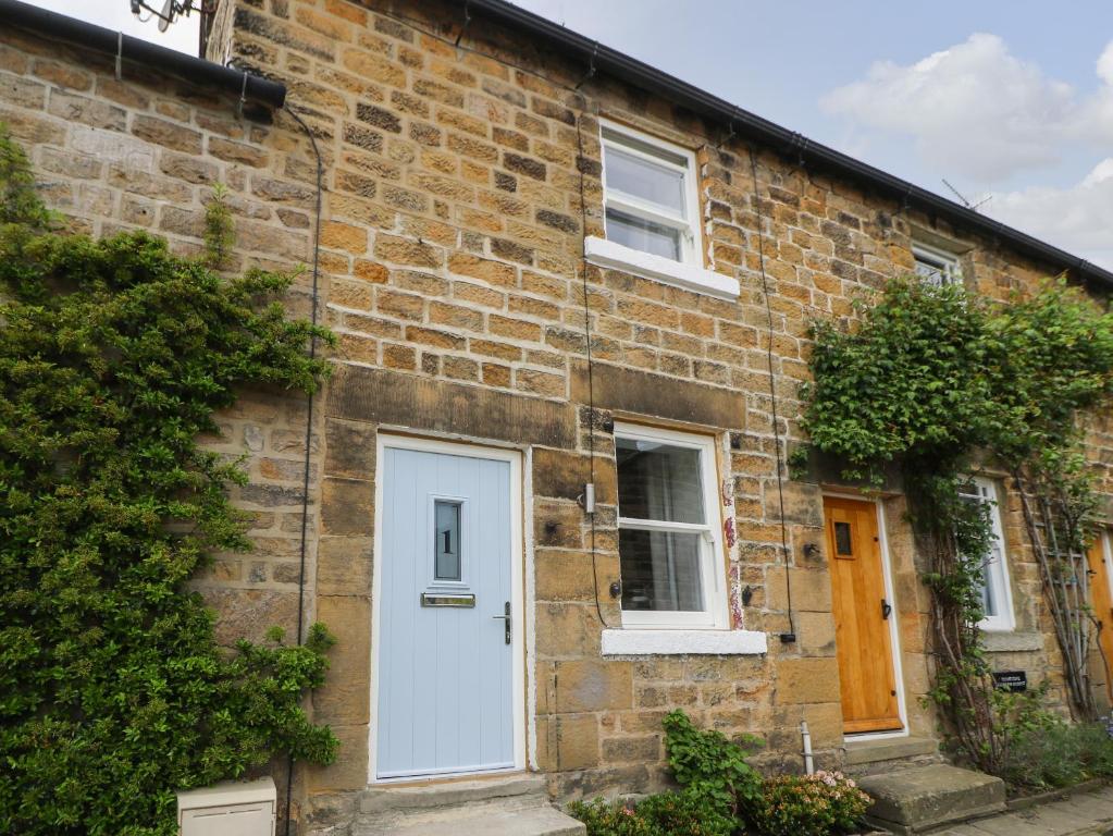a brick house with a white door and windows at Old Stone Cottage in Harrogate
