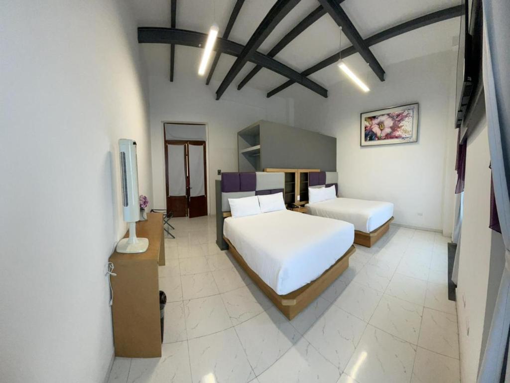a bedroom with two beds and a television in it at Hotel Alhaja in Puebla