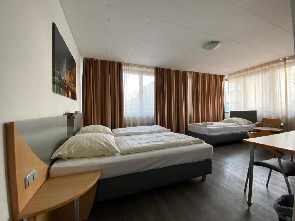 a bedroom with two beds and a desk and a table at Opera Hotel Köln in Cologne