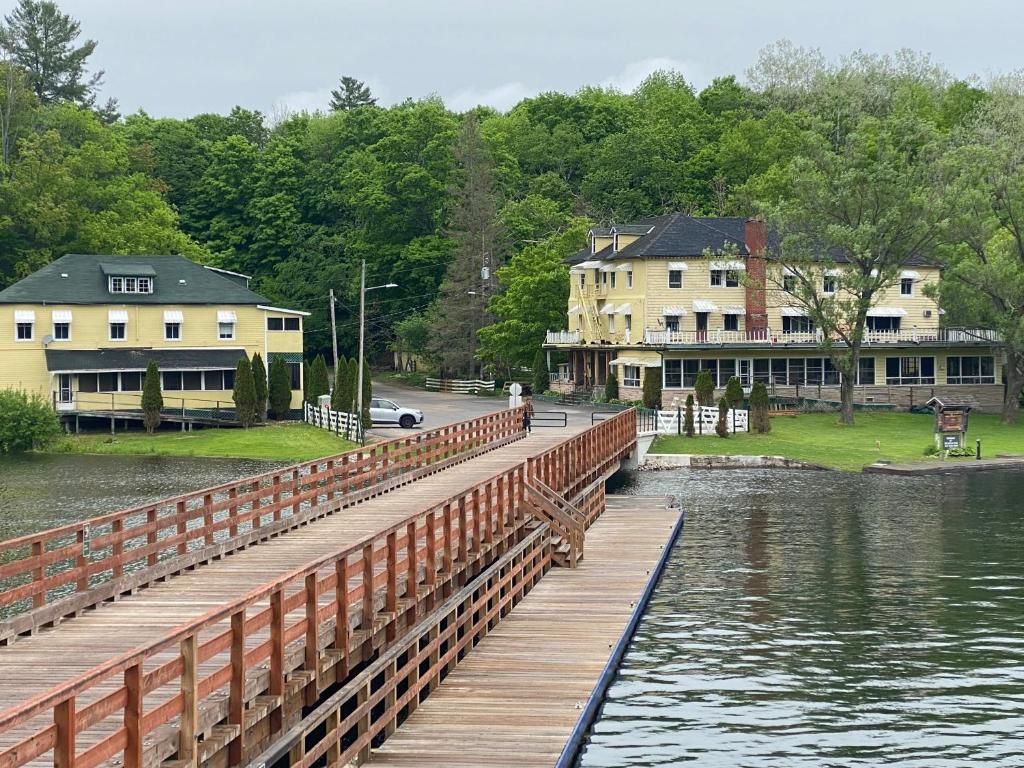 a wooden bridge over a body of water with houses at Hotel Kenney Rideau in Crosby