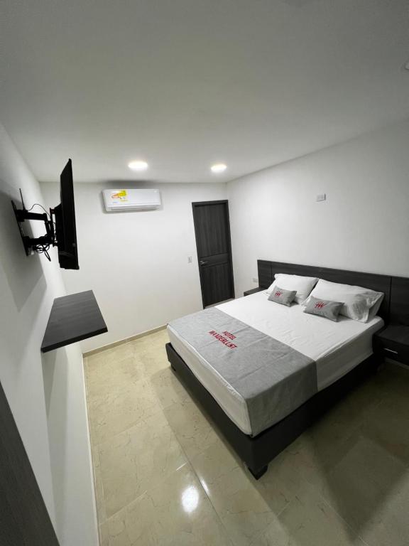 a bedroom with a bed in a white room at Hotel Wanderlust in Santa Marta