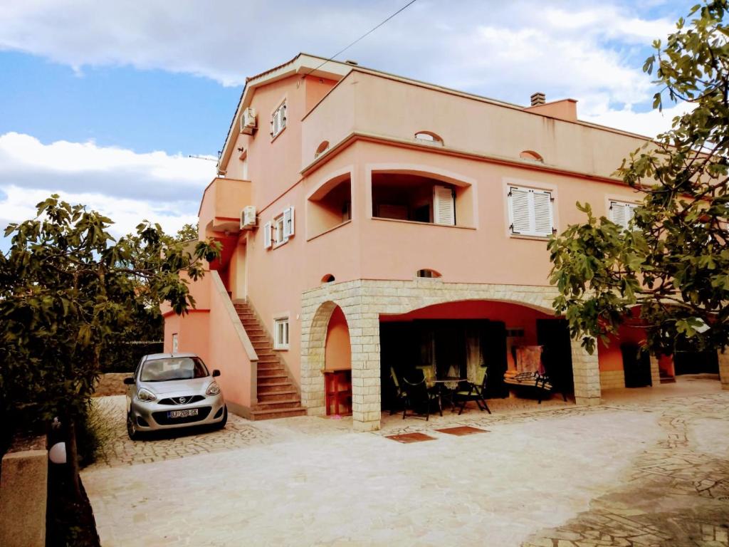 a house with a car parked in front of it at Apartments Ivanka G in Malinska